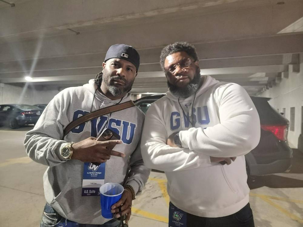 Two alumni in GVSU sweatshirts pose for a photo.